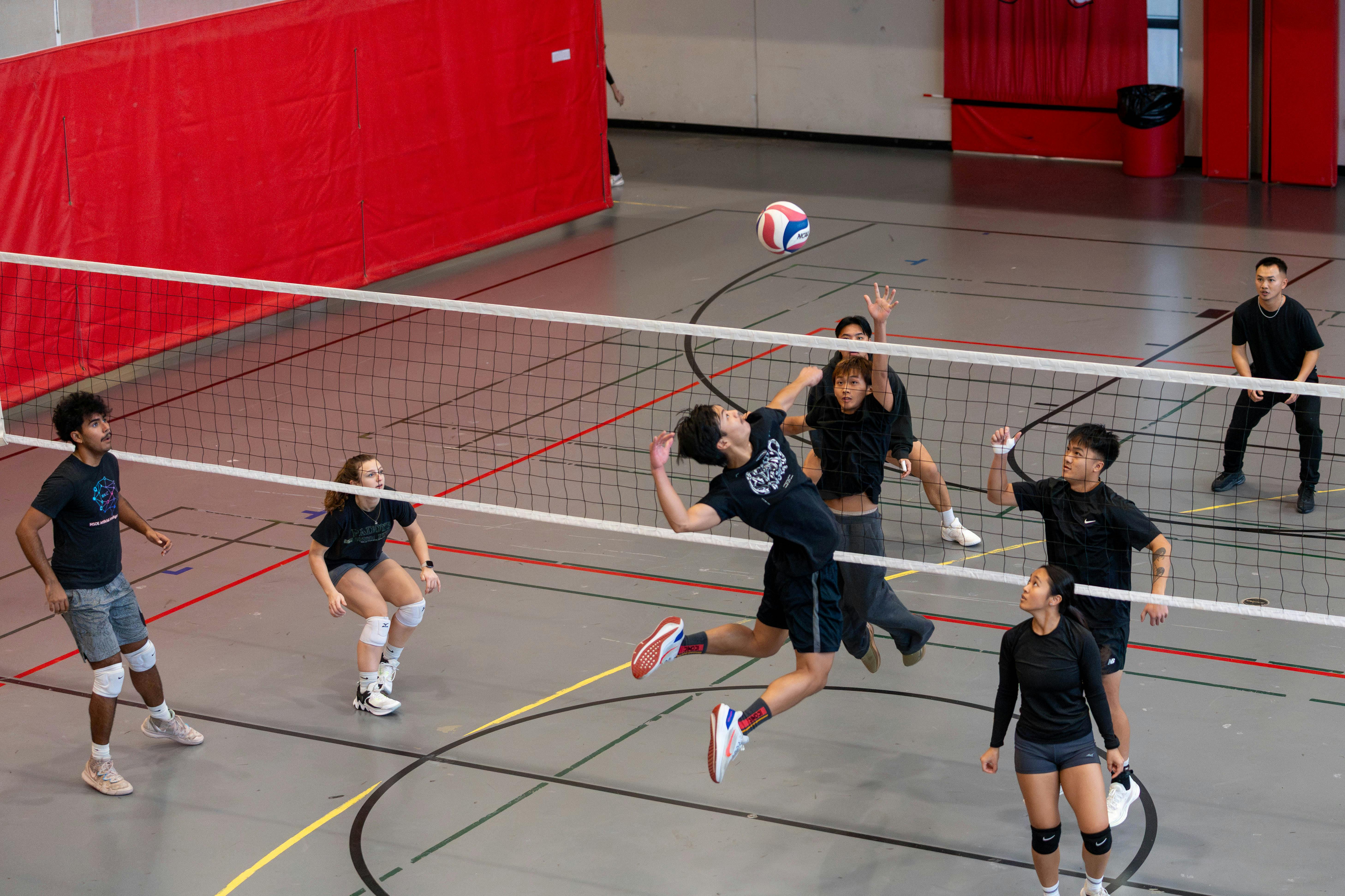 Teammates gathering around the court during a recreational volleyball game.